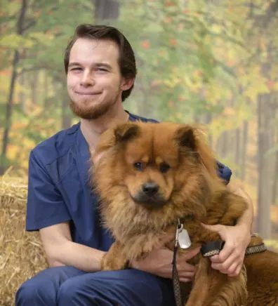 Brandon holding a fluffy orange Chow dog in his arms